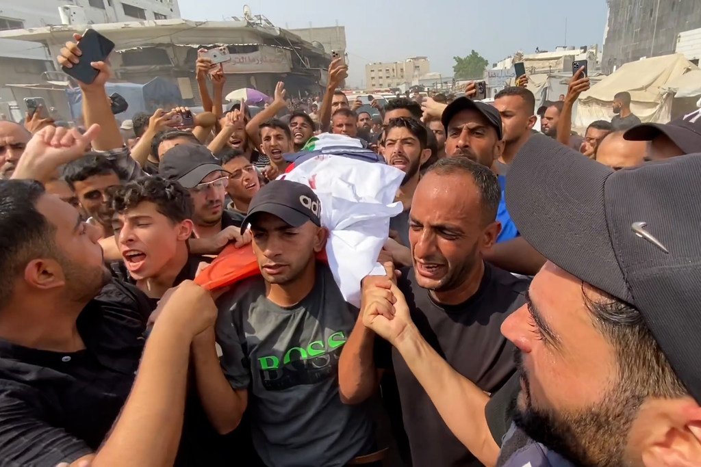 Le corps d'un journaliste tué lors d'une frappe israélienne sur Gaza, le 10 août 2025, est porté par une foule endeuillée.