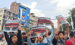 Young Nepalese protesters holding signs with slogans like '#WAKEUPNEPAL' and 'GEN Z WON'T BE SILENT' during a demonstration against corruption and social media restrictions in Kathmandu.