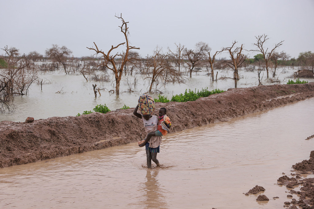 Des personnes déplacées par des inondations transportent leurs enfants et leurs biens le long d'une route inondée à Bentiu, au Soudan du Sud (photo d'archives).