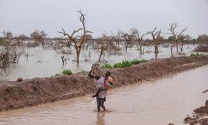 People displaced by flooding carry children and belongings along a waterlogged road in Bentui, South Sudan. (file)