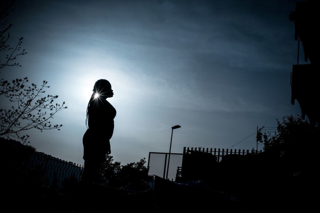 Silueta de una mujer nigeriana de perfil contra un cielo nublado y brillante en un entorno urbano.