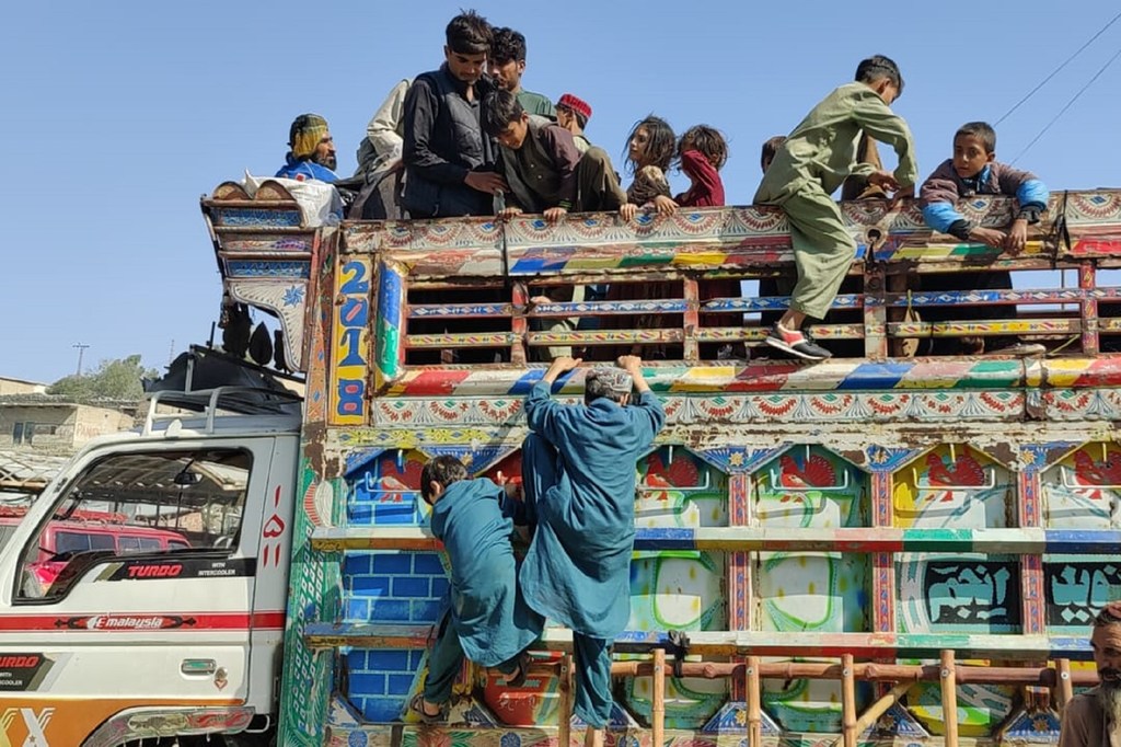 أطفال لعائلات أفغانية لاجئة يتسلقون شاحنة عائدة إلى أفغانستان.