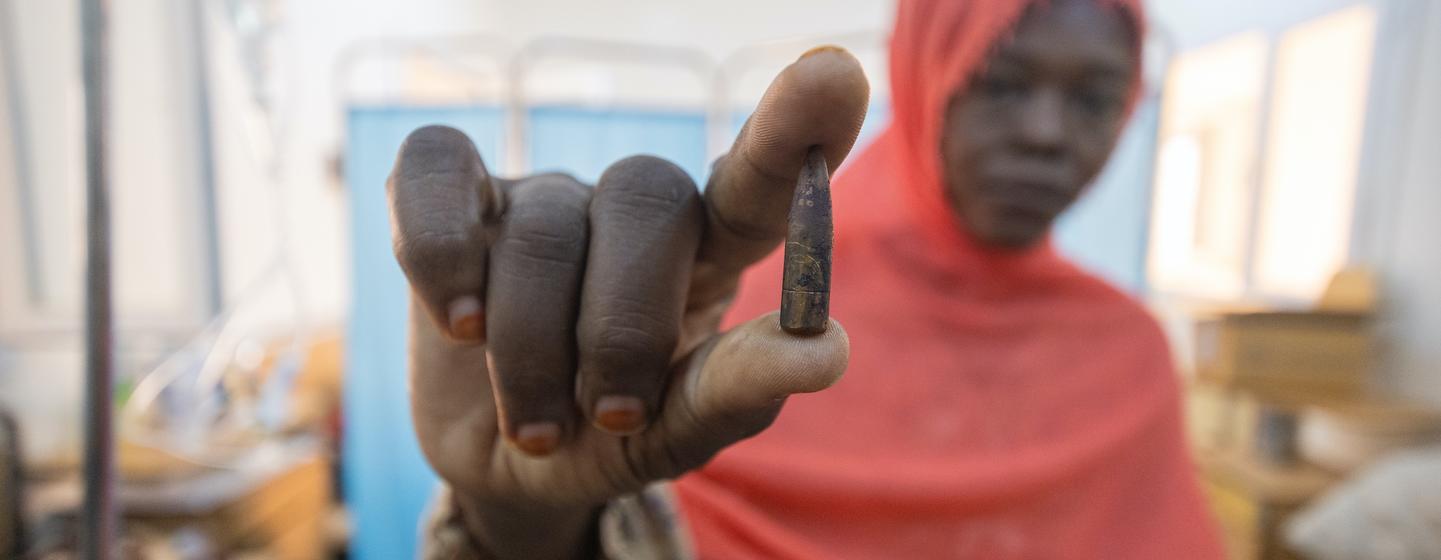 Une femme au Soudan tient une douille de balle dans sa main dans un établissement médical.