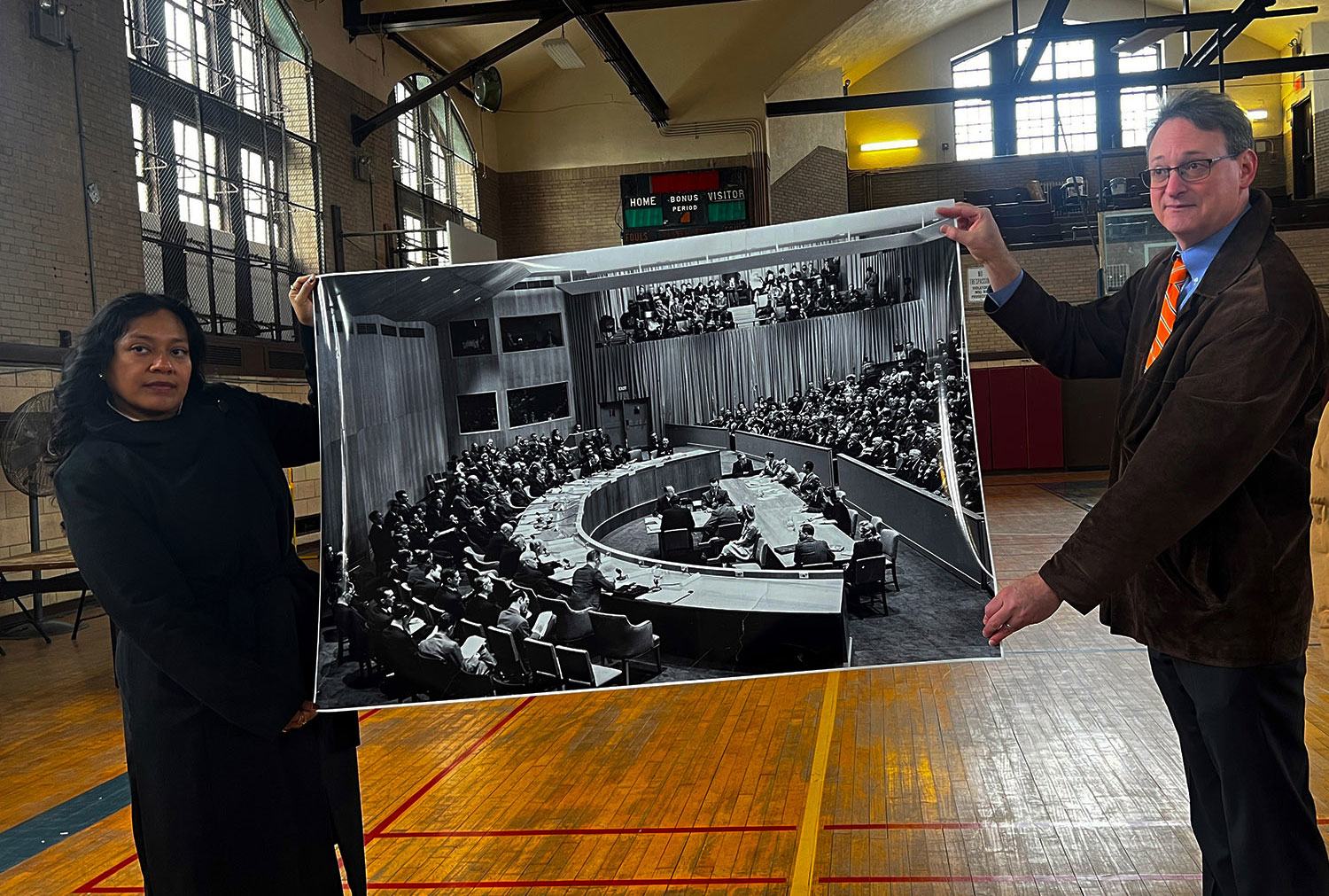 Two current-day employees of Lehman College hold a photograph of the UN Security Council from 1946 which once occupied the college's basketball court. Two current-day employees of Lehman College hold a photograph of the UN Security Council from 1946 which once occupied the college's basketball court.