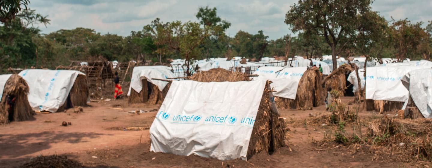 Um local de deslocados na aldeia de Kyoko, província de Tanganyika, República Democrática do Congo, com abrigos de emergência cobertos com lonas com a marca UNICEF.
