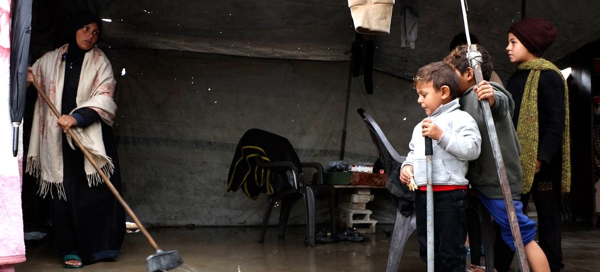 Une famille évacue l'eau de pluie de sa tente inondée dans un camp pour personnes déplacées à Gaza, après les fortes précipitations qu'a connu l'enclave ces derniers jours.