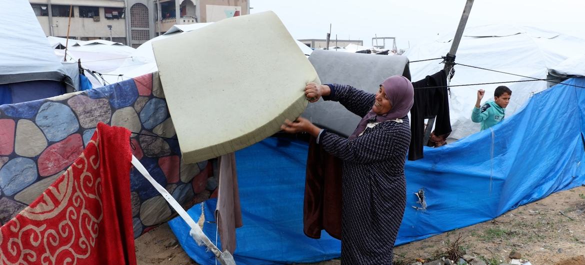 Amina Abdullah estava ao lado de sua tenda, agora inundada. Exausta, ela estendeu os cobertores encharcados em cordas para secar.