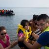 在北爱琴海地区的莱斯博斯岛，一名志愿者帮助新抵达的难民从一艘大型橡皮艇上下船。（资料图片）
