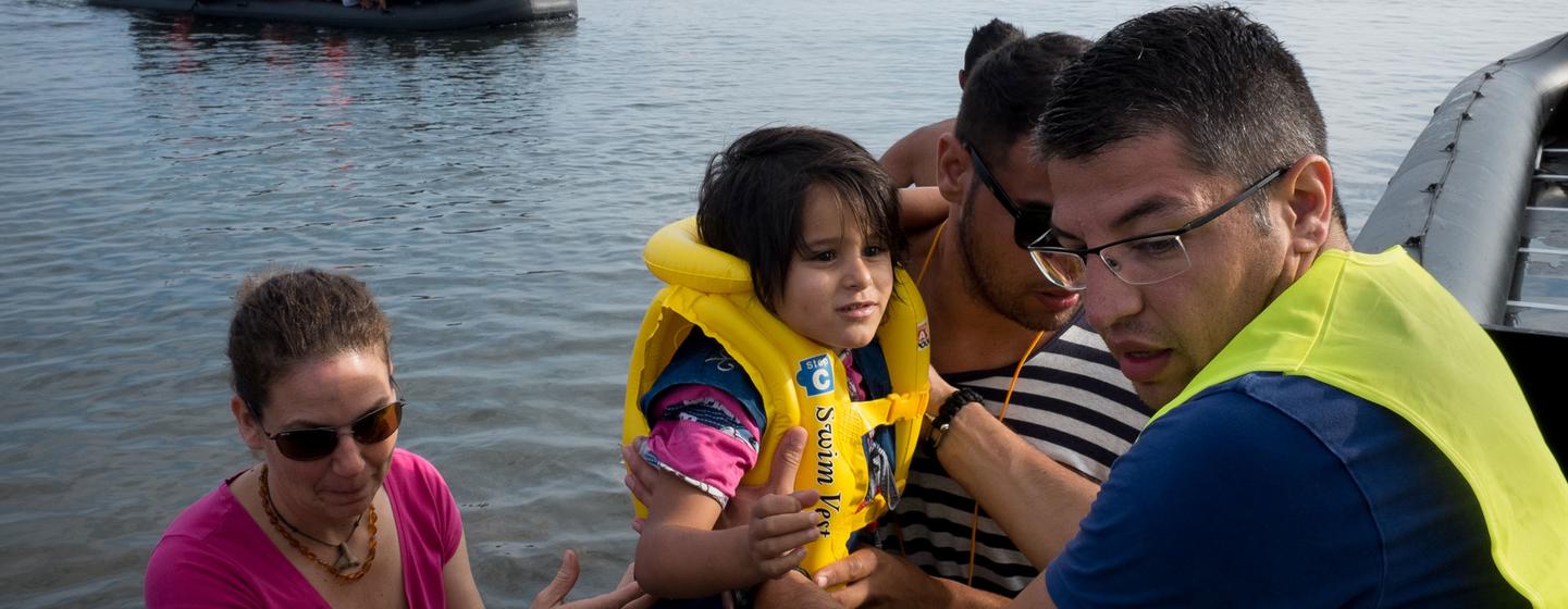 Un volontaire aide les réfugiés nouvellement arrivés à débarquer d'un grand canot pneumatique, sur l'île de Lesbos, dans la région de l'Égée du Nord (photo d'archives).