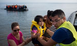  A volunteer helps newly arrived refugees disembark from a large rubber boat, on the island of Lesbos, in the North Aegean region. (file)