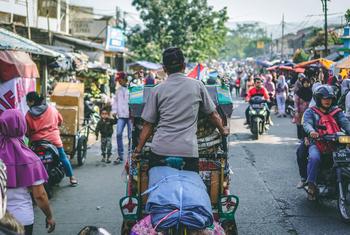 Un homme sur un pousse-pousse dans une rue animée de la ville de Bandung, en Indonésie.