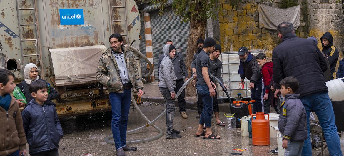 Des familles remplissent des jerrycans d'eau potable à un point de distribution dans le quartier d'Almyassar, dans la ville d'Alep, dans le nord de la Syrie.