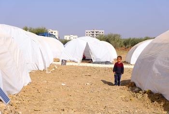 在叙利亚西北部的阿扎兹，一名儿童站在为流离失所家庭新建的营地帐篷之间。 