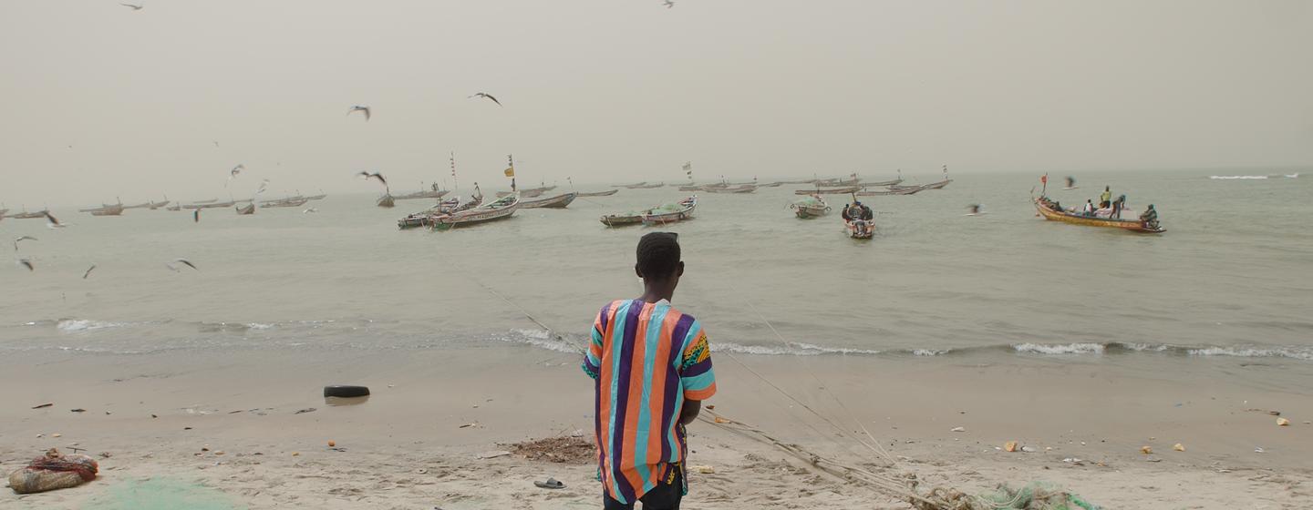 Amadou Jobe, a returning migrant, looking out to the Pacific ocean from the Gambian coast.