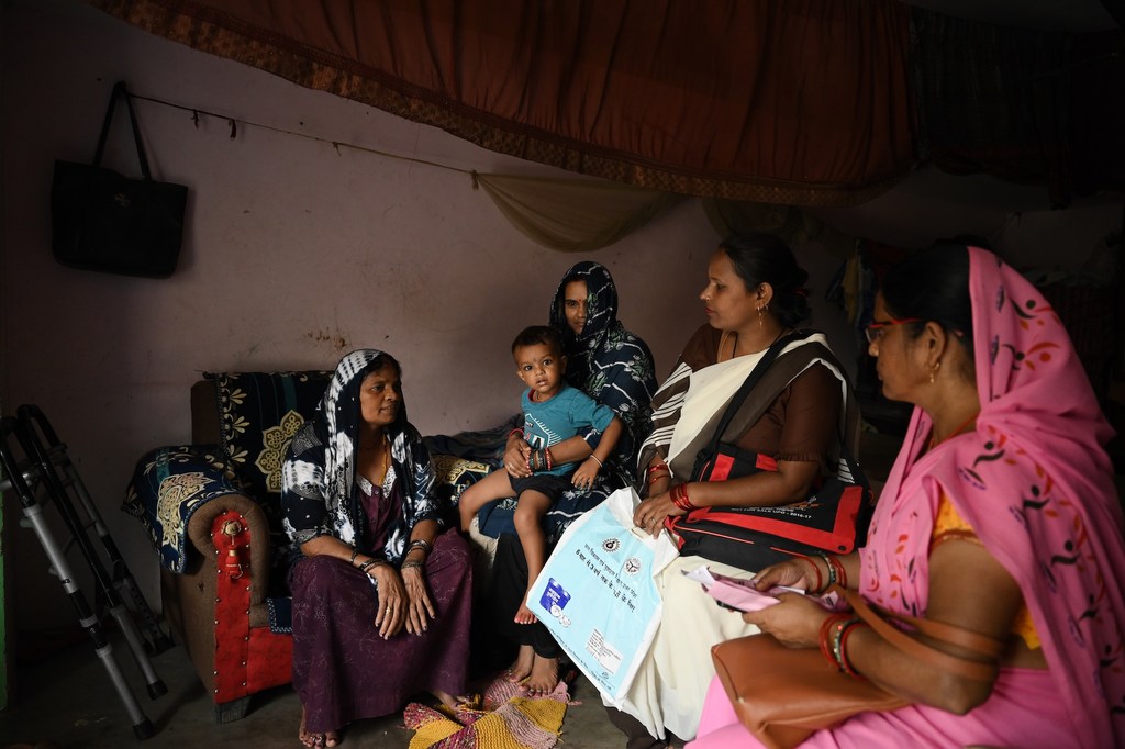 यूनिसेफ के दस्तक कार्यक्रम की एक सामाजिक कार्यकर्ता ग्रामीण भारत में घर-घर जाकर एक परिवार को सहायता वितरित कर रही है।