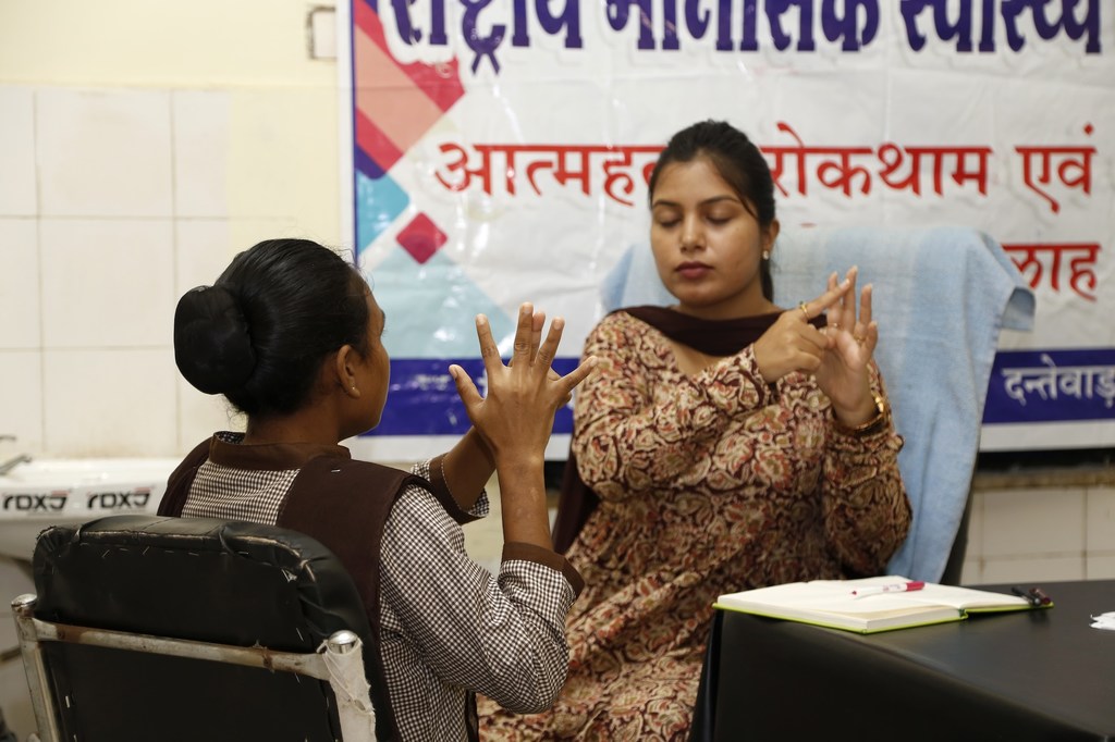 एक स्थानीय स्वास्थ्य केंद्र में एक महिला परामर्शदाता एक महिला ग्राहक के साथ मनोसामाजिक सत्र के दौरान सांकेतिक भाषा का उपयोग करती है।