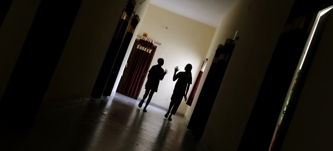 Two young girls walk through the corridor to attend a psychosocial group session.