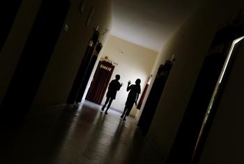 Duas meninas, de 13 e 15 anos, caminham pelo corredor para participar de uma sessão de grupo psicossocial em Dantewada, Chhattisgarh, Índia