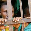 Deux jeunes garçons africains regardent à travers les barreaux d'une cellule de prison à Abomey, au Bénin.