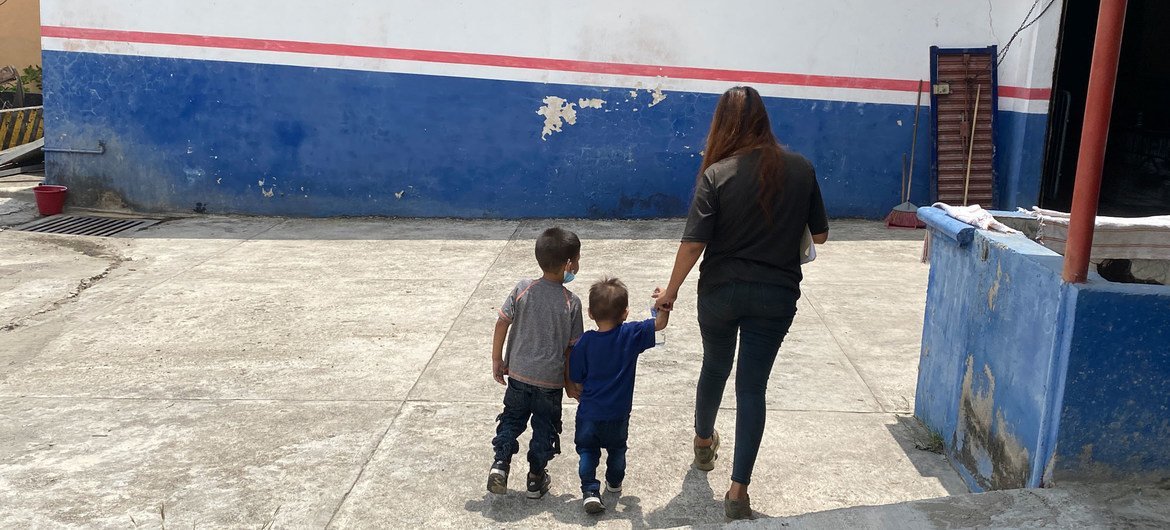 Una madre salvadoreña y sus dos hijos pequeños caminan por un centro de registro del ACNUR en el sur de México.
