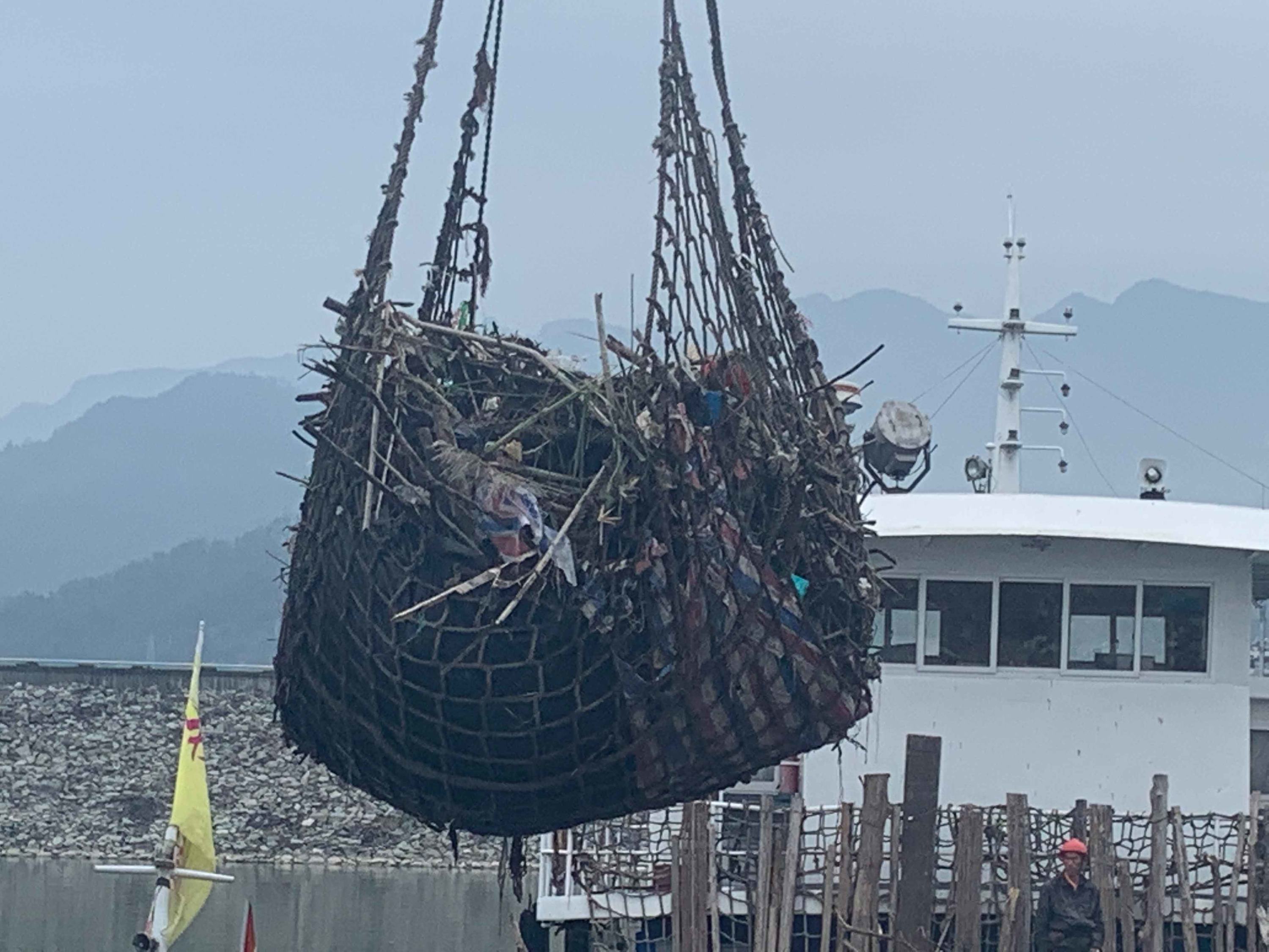 一些被打捞上来的漂浮物正在被吊起。
