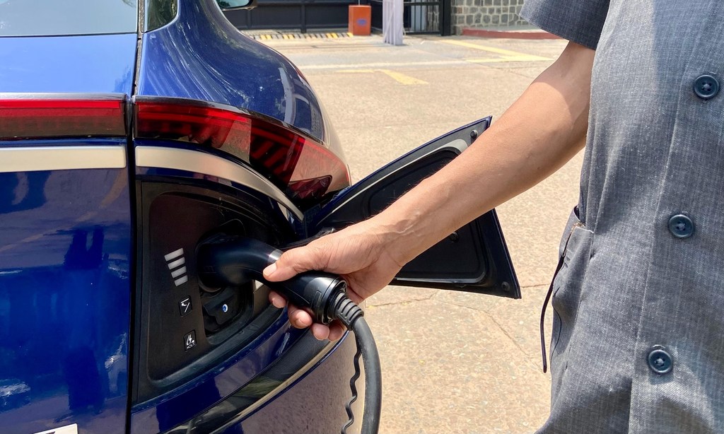 Um homem conecta um veículo elétrico a uma tomada de carregamento em um sistema de monitoramento de energia em Nova Delhi.