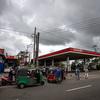 Une longue file d'attente de voitures et de tuk-tuks à une station-service du CIO au Sri Lanka sous un ciel nuageux, illustrant la pénurie de carburant dans le pays.