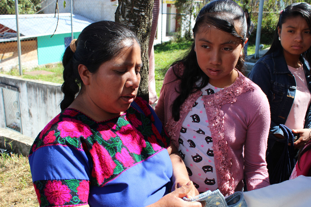 Tres mujeres, una de ellas vestida con ropa tradicional bordada, participan en un taller del UNDP en México.