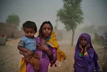 عائلة من قرية إسماعيل بهاند في باكستان ، التي تضررت بشدة من الفيضانات، تشق طريقها إلى عيادة صحية متنقلة خلال عاصفة رملية.