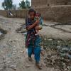 在村庄被洪水摧毁后，巴基斯坦一名年轻女孩抱着一个孩子前往一家流动医疗诊所。