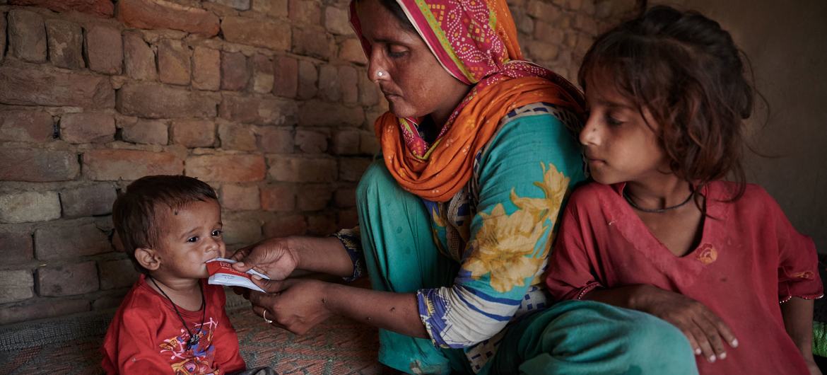 Una madre alimenta a un niño desnutrido en su casa, en un pueblo devastado por las inundaciones en Pakistán