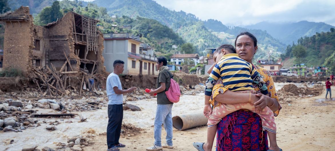 Uma mãe conforta o seu filho numa cidade nos arredores de Katmandu, capital do Nepal, depois de fortes chuvas e inundações repentinas que afetaram dezenas de milhares de famílias.