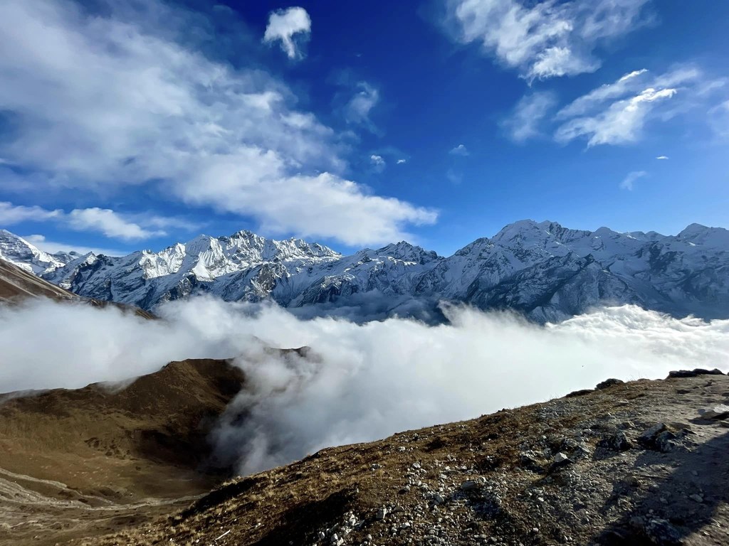 Milima yenye theluji ya eneo la Langtang huko Nepal, huku mawingu yakipita kwenye bonde chini.