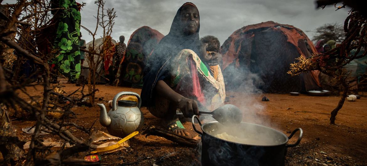 Une mère fait la cuisine pour ses enfants dans un camp de personnes déplacées à Dollow, en Somalie.