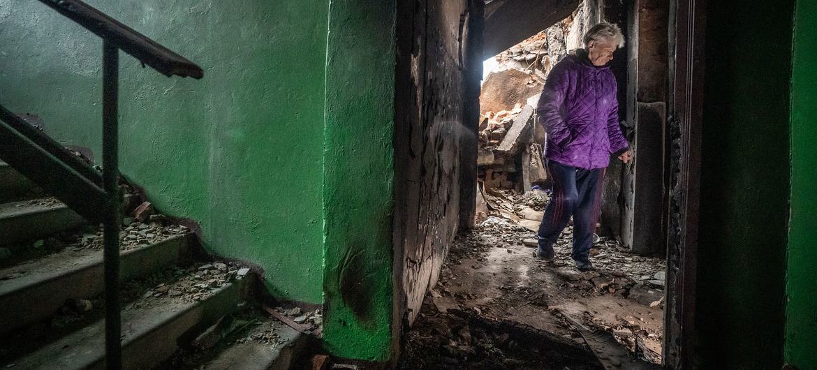 यूक्रेन के एक इलाक़े में युद्ध से हुई तबाही को देखते हुए एक महिला
