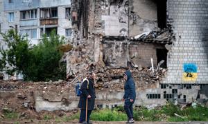Women talk outside a residential building damaged by airstrikes in the Kyiv suburb of Borodyanka.