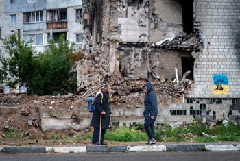 在基辅郊区，妇女们在一栋被空袭损坏的住宅楼外交谈。
