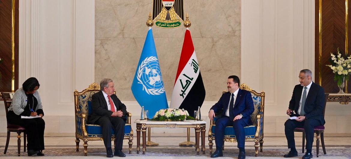 UN Secretary-General Antonio Guterres meets with Iraqi Prime Minister Mohammed Al-Sudani in a formal diplomatic meeting, seated opposite each other with UN and Iraqi flags between them.