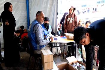 موظفو الأونروا يقدمون المساعدات للنازحين في مركز لإيوا النازحين بمدرسة دير البلح الإعدادية في غزة.