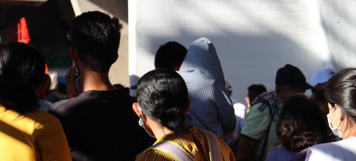 Vista de trás de uma multidão de pessoas, incluindo uma jovem com uma mochila, em fila para se abrigar no Estádio General Santander em Cúcuta.