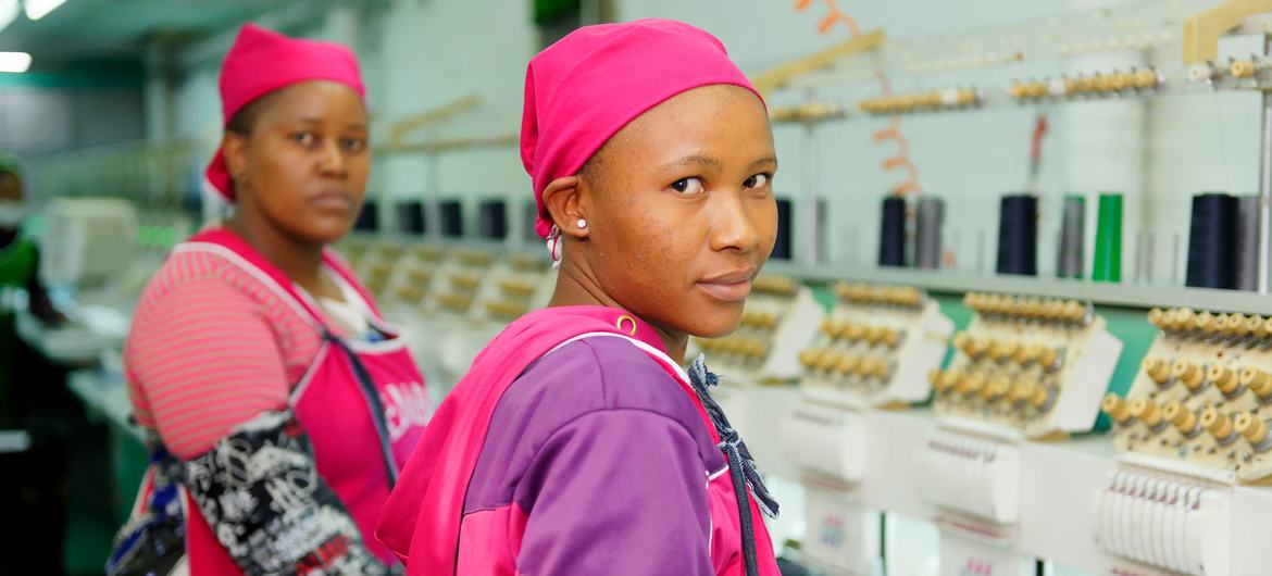 Garment workers stand next to a line of sewing machines in a clothing plant in Lesotho.