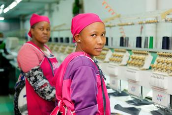 Garment workers stand next to a line of sewing machines in a clothing plant in Lesotho.