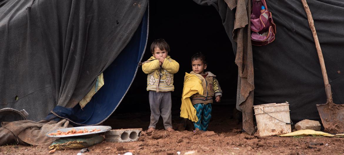 Des enfants déplacés se tiennent devant la tente de leur famille dans un camp informel du sud de la Syrie.