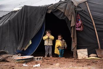 Des enfants déplacés se tiennent devant la tente de leur famille dans un camp informel du sud de la Syrie.