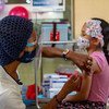 Una trabajadora sanitaria administra una vacuna a una niña pequeña en un entorno clínico.