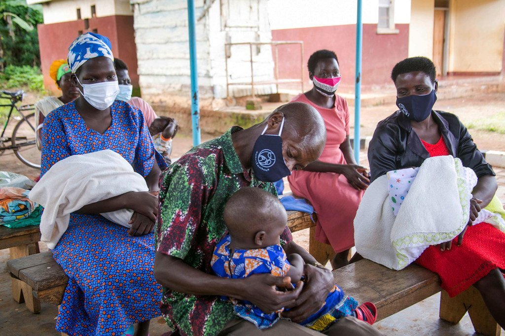 Nathan Lutaaya, père séropositif, tient son bébé dans ses bras en attendant avec d'autres parents une séance d'éducation sanitaire au centre de santé Namwendwa IV à Kamuli, en Ouganda, animée par la mère mentor Sarah Nabirye.
