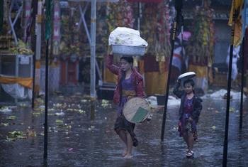 一对母亲和她的女儿走在市场上，试图避雨。