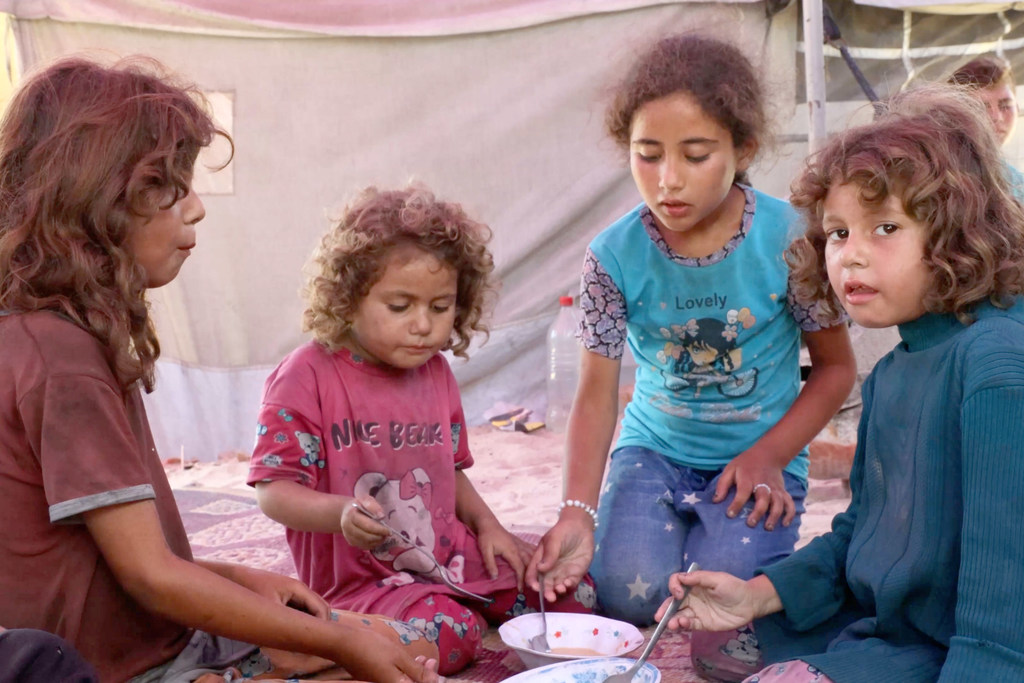 Niños desplazados comiendo sopa de lentejas dentro de un edificio destruido en Gaza.
