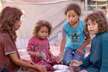 بنات السيدة هيام يتناولن وجبة الغداء من شوربة العدس، من دون خبز، في مكان سكنهن، داخل مبنى مدمر.