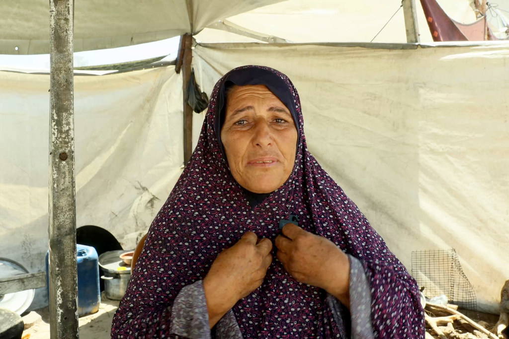 Badriya Barrawi, una persona desplazada en Gaza, se encuentra dentro de una tienda de campaña improvisada entre las ruinas de edificios destruidos.